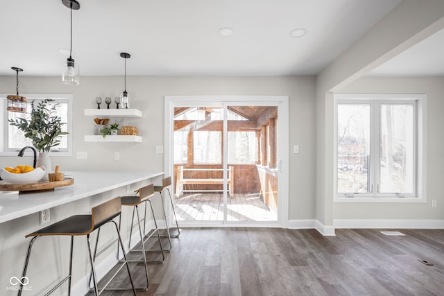 interior space featuring a breakfast bar area, dark hardwood / wood-style flooring, and hanging light fixtures