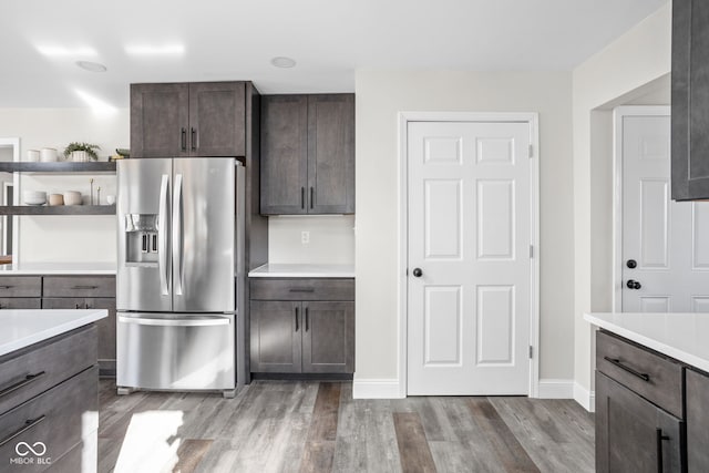 kitchen with stainless steel fridge, dark brown cabinetry, and hardwood / wood-style flooring