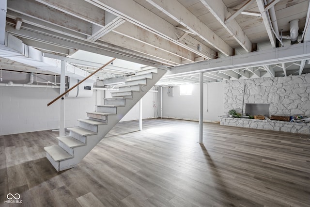 basement featuring a stone fireplace and wood-type flooring