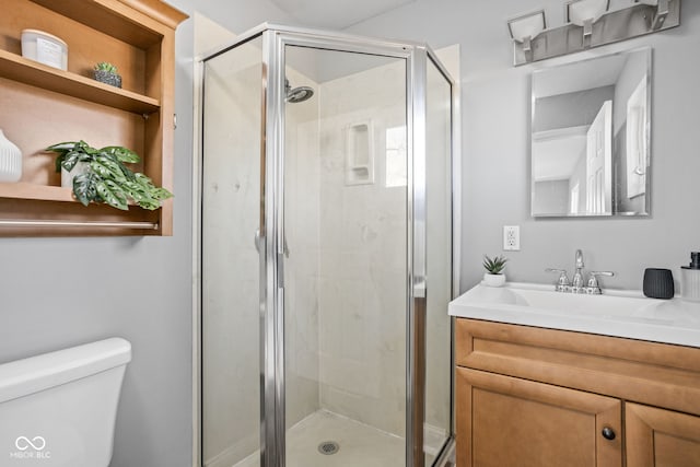 bathroom featuring vanity, toilet, and a shower with door