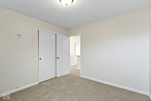 unfurnished bedroom with light carpet, a textured ceiling, and a closet