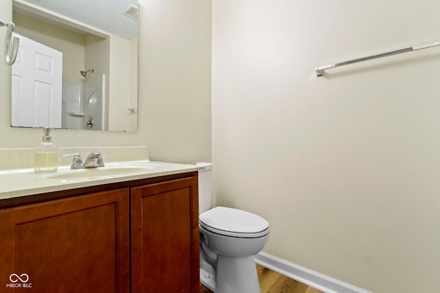 bathroom with a shower, hardwood / wood-style floors, vanity, and toilet