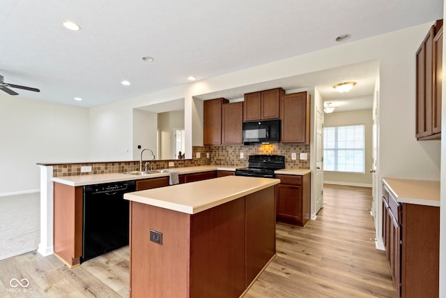 kitchen with light hardwood / wood-style floors, a center island, black appliances, and sink