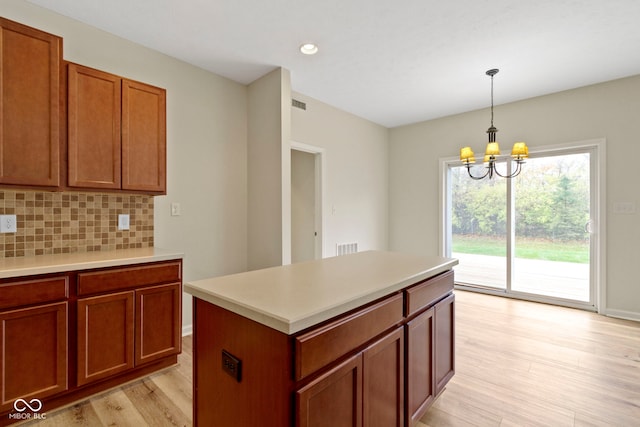 kitchen featuring decorative backsplash, a chandelier, a center island, light hardwood / wood-style floors, and hanging light fixtures