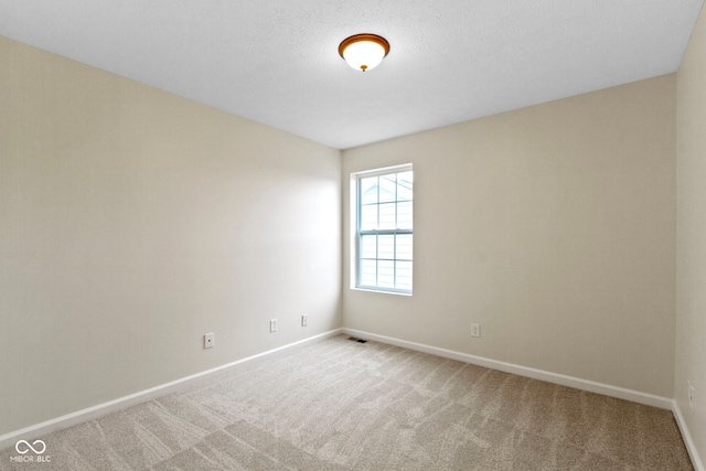 carpeted empty room with a textured ceiling