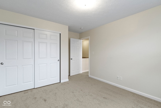 unfurnished bedroom featuring a closet, light colored carpet, and a textured ceiling