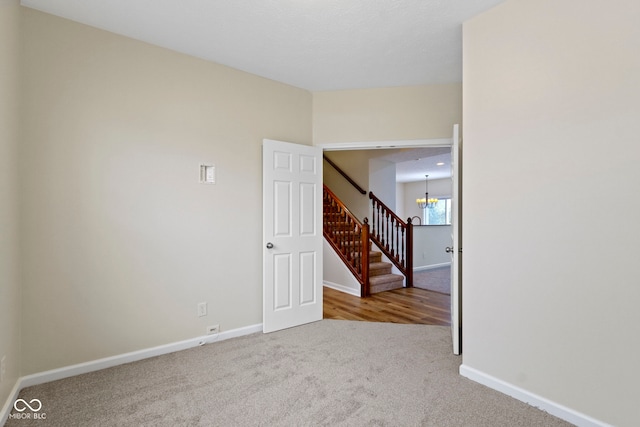 unfurnished room with carpet flooring and a notable chandelier