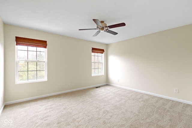 spare room featuring plenty of natural light, ceiling fan, and light colored carpet