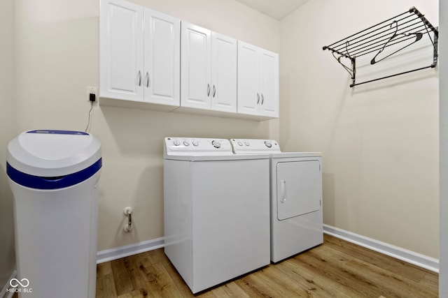 laundry area with washer and clothes dryer, light hardwood / wood-style flooring, and cabinets