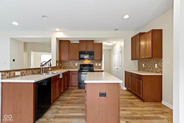 kitchen featuring backsplash, black appliances, sink, light hardwood / wood-style floors, and a kitchen island