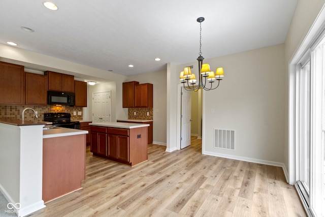 kitchen featuring black appliances, decorative light fixtures, light hardwood / wood-style flooring, a notable chandelier, and a kitchen island