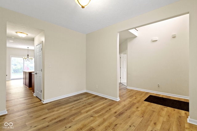 empty room featuring a chandelier and light hardwood / wood-style flooring