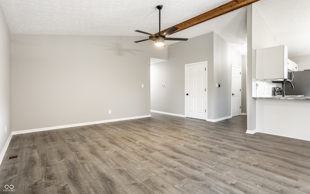 unfurnished living room featuring high vaulted ceiling, sink, ceiling fan, a textured ceiling, and wood-type flooring