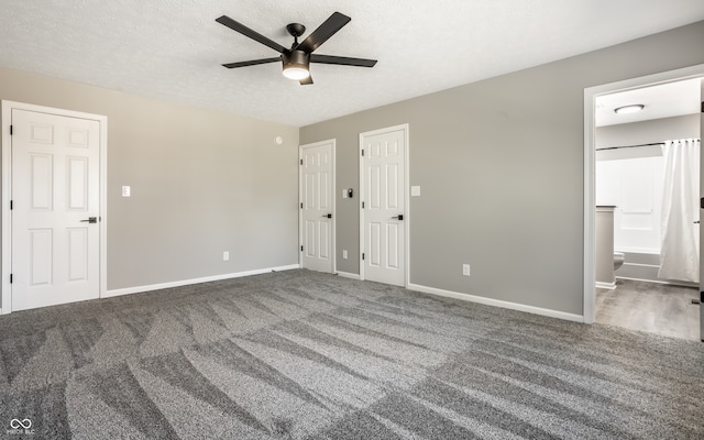 interior space featuring ensuite bath, ceiling fan, a textured ceiling, and dark colored carpet