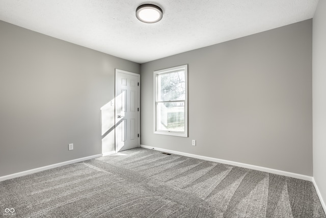 empty room with a textured ceiling and carpet floors