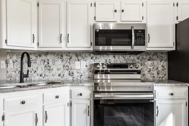 kitchen featuring backsplash, white cabinetry, sink, and appliances with stainless steel finishes