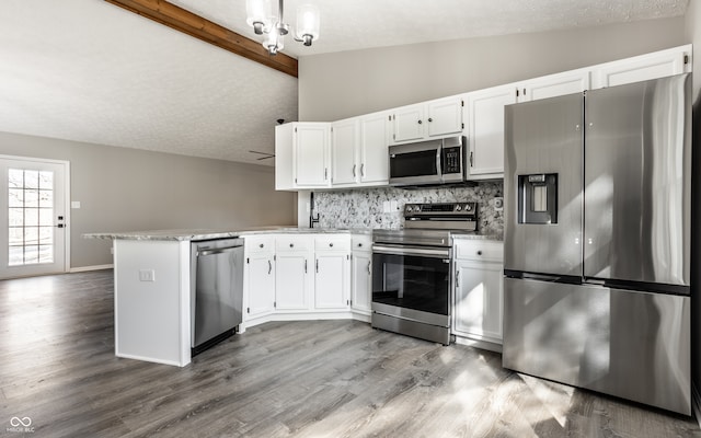 kitchen with vaulted ceiling with beams, white cabinets, light wood-type flooring, and appliances with stainless steel finishes