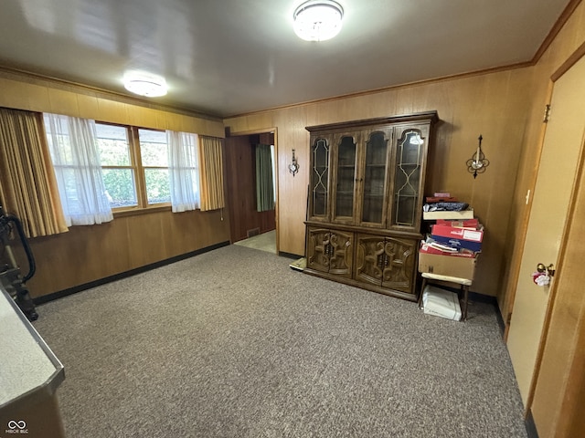 interior space featuring carpet flooring, ornamental molding, and wooden walls