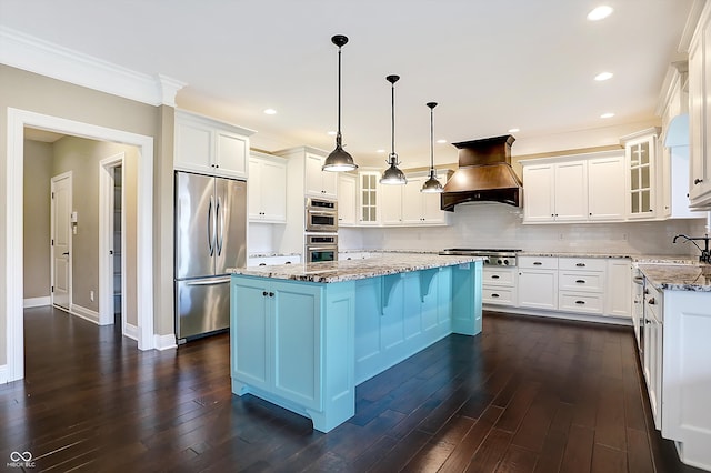 kitchen featuring dark hardwood / wood-style flooring, a kitchen island, light stone countertops, appliances with stainless steel finishes, and premium range hood