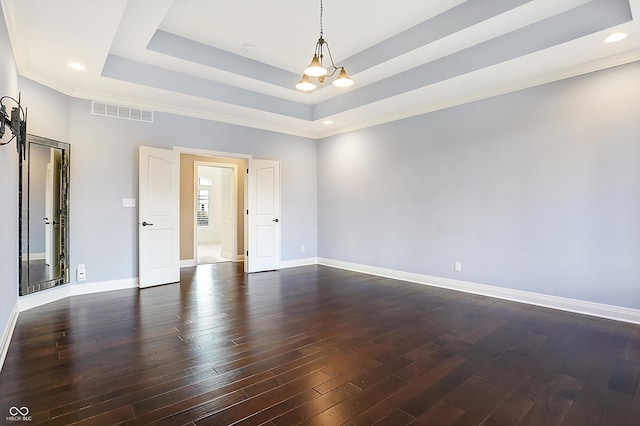 spare room with dark hardwood / wood-style floors, a tray ceiling, and a notable chandelier