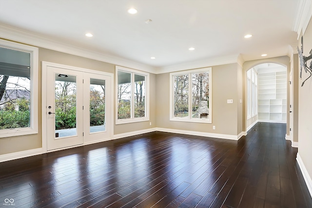 empty room with a wealth of natural light, dark hardwood / wood-style floors, and crown molding