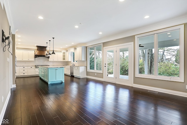 kitchen with dark hardwood / wood-style flooring, crown molding, a kitchen island, decorative light fixtures, and premium range hood