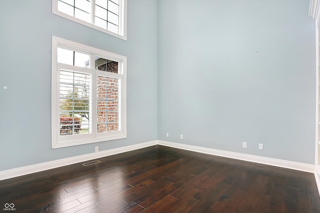 spare room featuring dark hardwood / wood-style floors and a towering ceiling