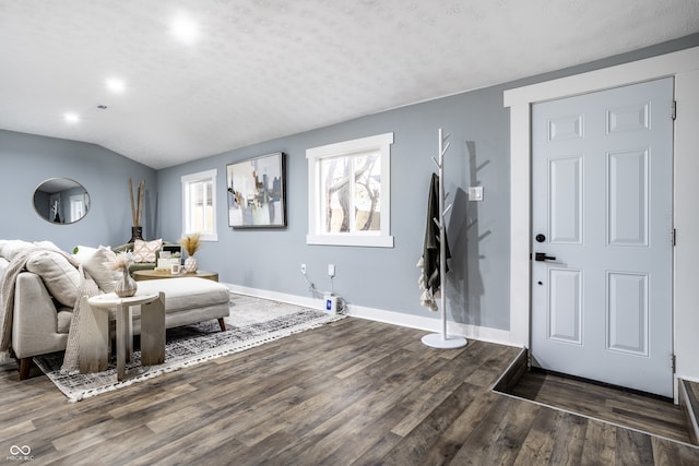 foyer entrance featuring a textured ceiling, dark wood-type flooring, and vaulted ceiling