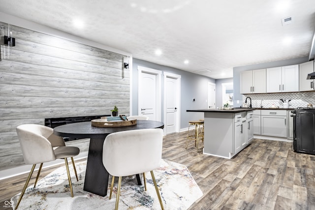 kitchen featuring a breakfast bar, wooden walls, white cabinetry, light hardwood / wood-style flooring, and a kitchen island