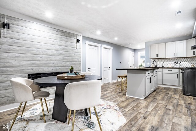 1621 Draper St, Indianapolis, IN 46203 - kitchen with dark countertops, wood finished floors, black range oven, a breakfast bar, and recessed lighting