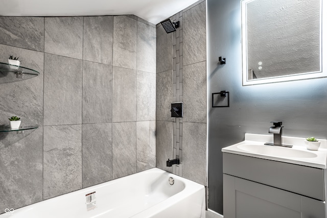 bathroom with vanity, tiled shower / bath, and lofted ceiling