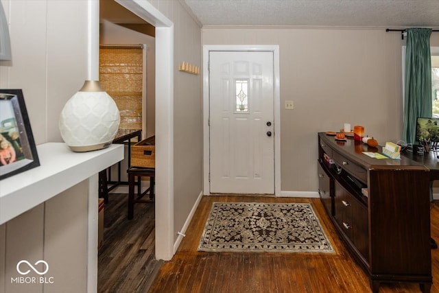 entrance foyer with crown molding, dark wood-type flooring, and a textured ceiling