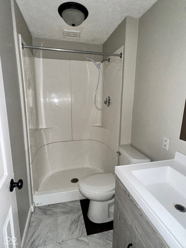 bathroom with walk in shower, vanity, toilet, and a textured ceiling