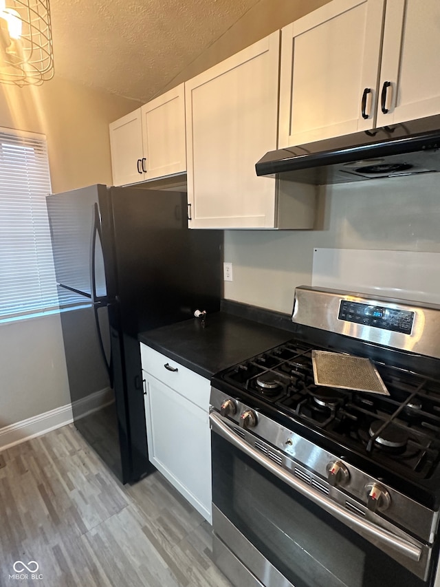 kitchen with white cabinetry, appliances with stainless steel finishes, a textured ceiling, and light wood-type flooring