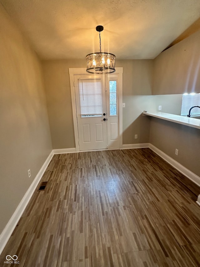 foyer entrance with dark wood-type flooring, a chandelier, and sink