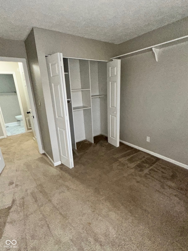 unfurnished bedroom with carpet floors, a textured ceiling, and a closet