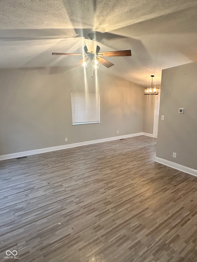 spare room featuring a textured ceiling, dark hardwood / wood-style floors, and ceiling fan with notable chandelier