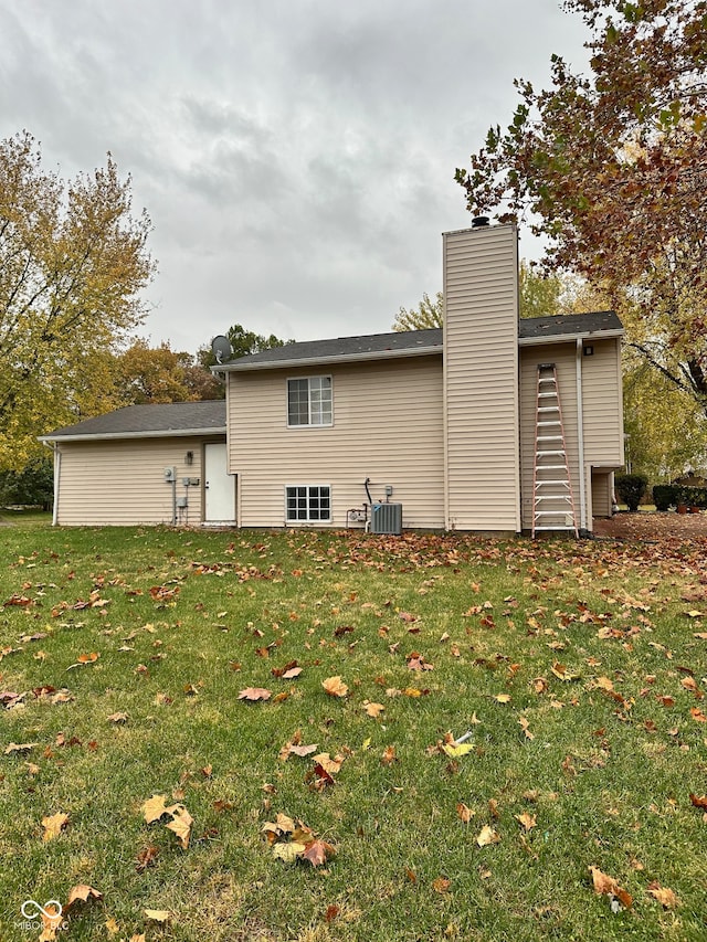 rear view of house featuring a lawn and central AC