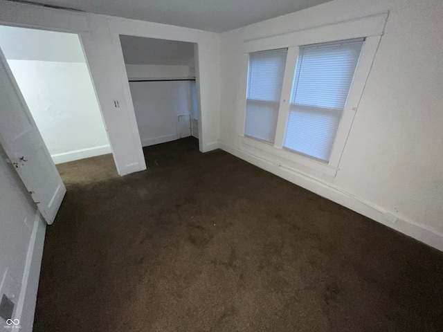 unfurnished bedroom with a closet and dark carpet