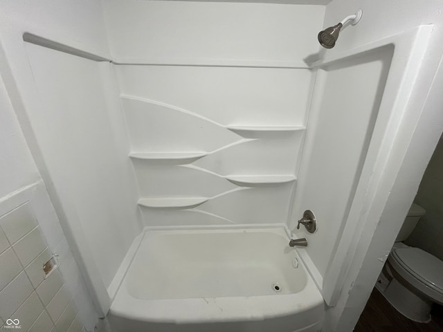 bathroom featuring toilet and tiled shower / bath combo