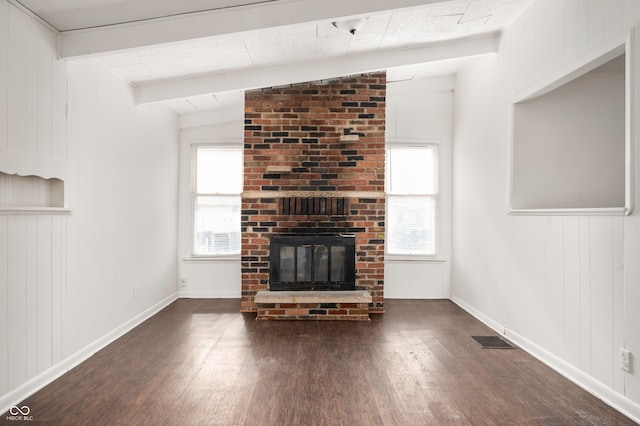 unfurnished living room featuring lofted ceiling with beams, a brick fireplace, dark wood-type flooring, and a wealth of natural light