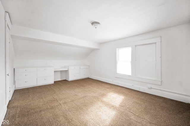 bonus room with lofted ceiling and carpet flooring