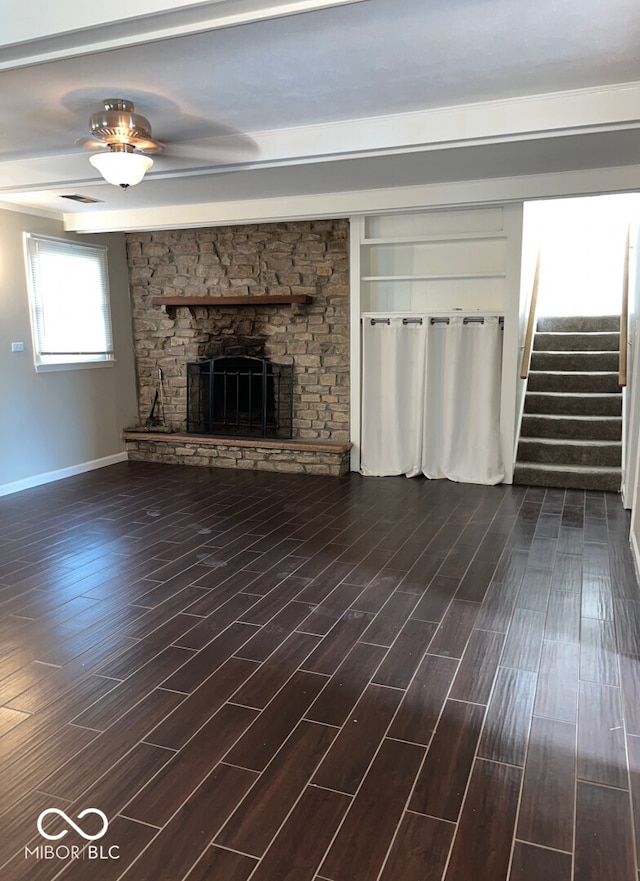 unfurnished living room with dark hardwood / wood-style flooring and a stone fireplace