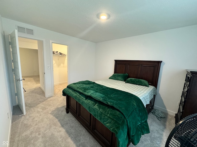 carpeted bedroom featuring a textured ceiling, a closet, and a walk in closet