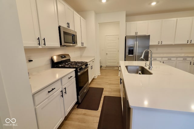 kitchen featuring white cabinetry, appliances with stainless steel finishes, sink, and light hardwood / wood-style floors