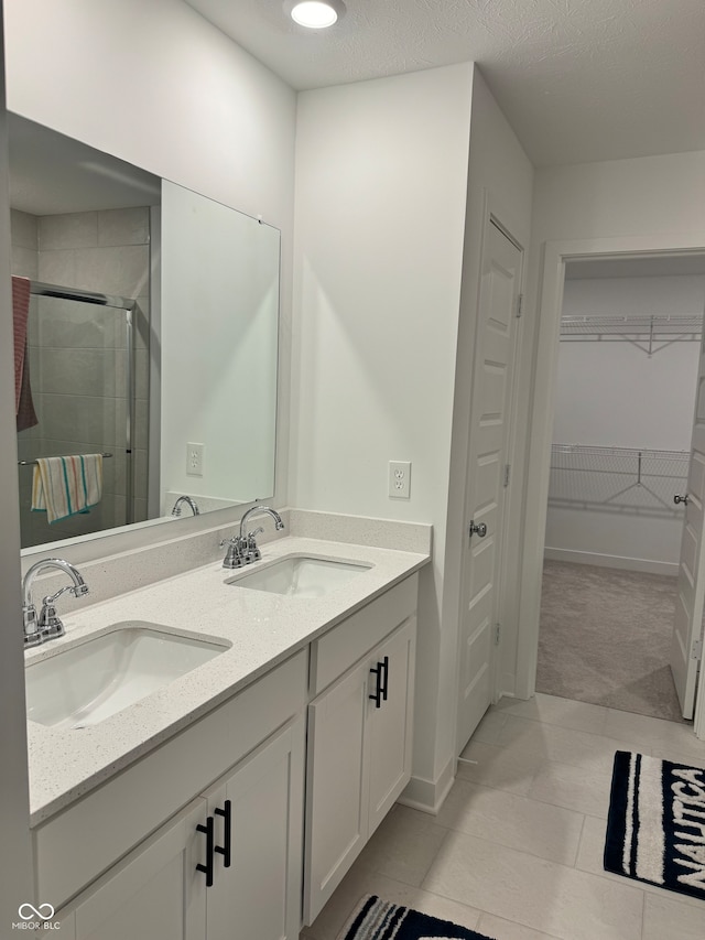 bathroom with a shower with door, vanity, tile patterned floors, and a textured ceiling