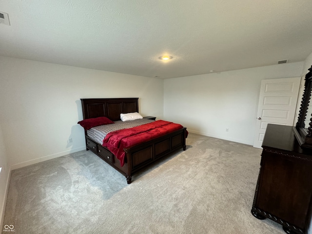 bedroom with light colored carpet and a textured ceiling