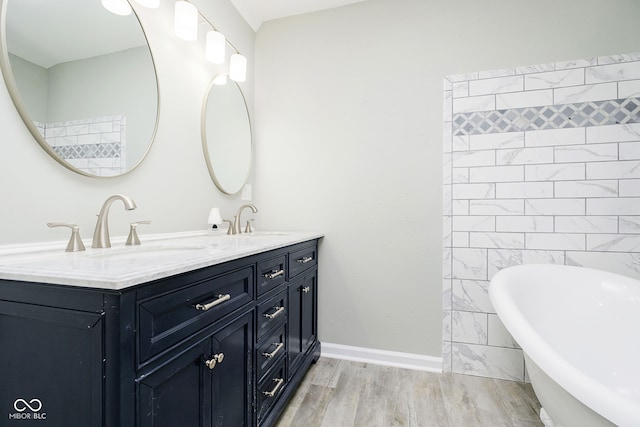 bathroom featuring hardwood / wood-style flooring, a tub to relax in, vanity, and tile walls