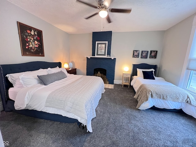 bedroom with a textured ceiling, dark colored carpet, ceiling fan, and a fireplace