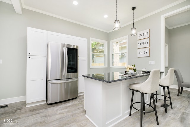 kitchen with stainless steel refrigerator, white cabinetry, ornamental molding, dark stone counters, and light wood-type flooring